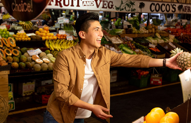 An international student purchasing a pineapple at the Adelaide Central Market